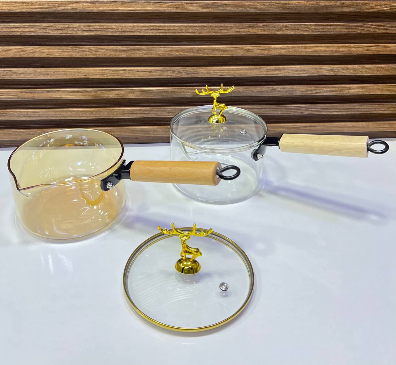Casserole en verre borosilicate transparent avec poignée en bois.